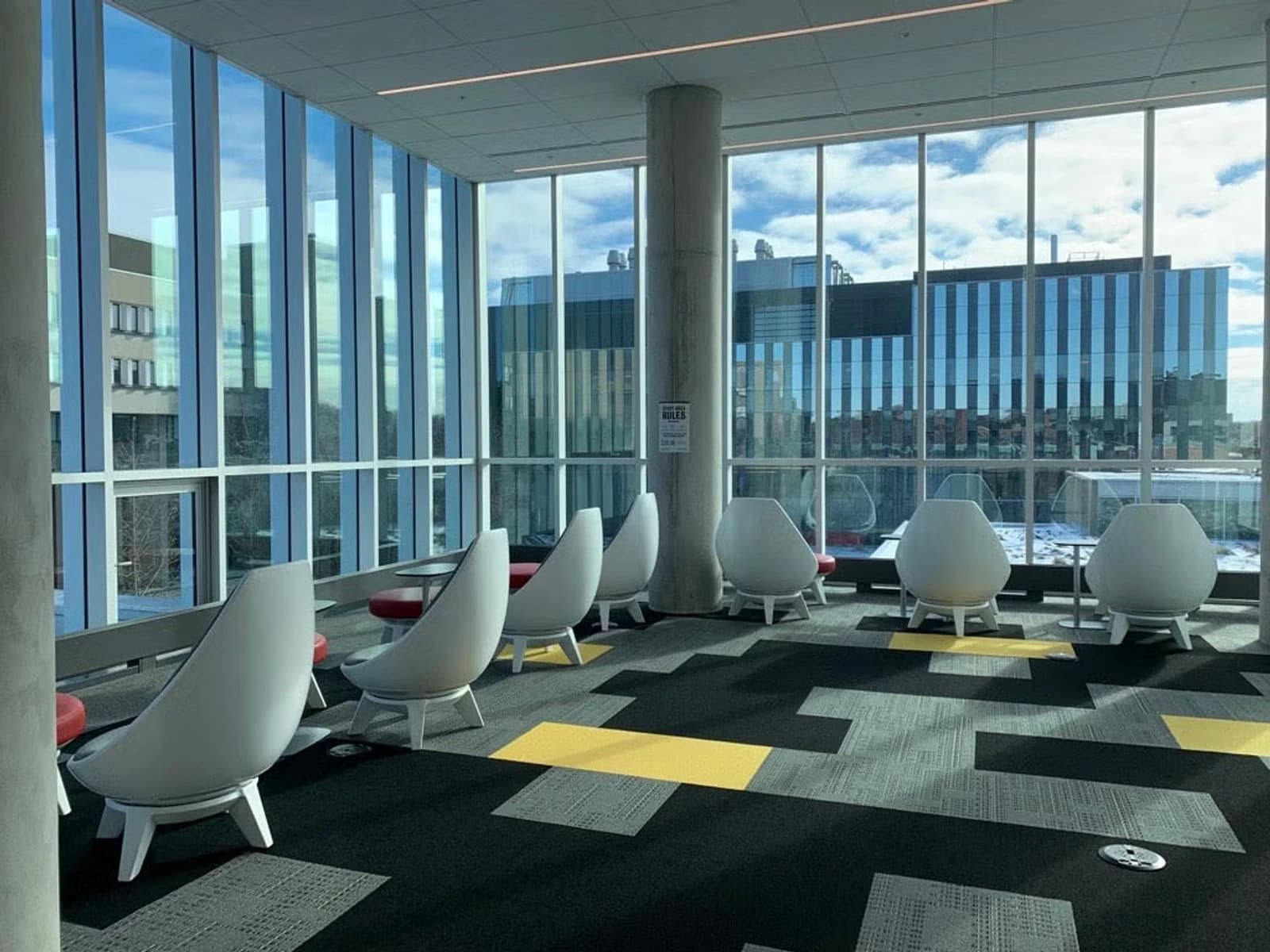 The upper lounge inside Waterloo's Student Life Centre, with black-and-gold flooring and campus buildings beyond the windows